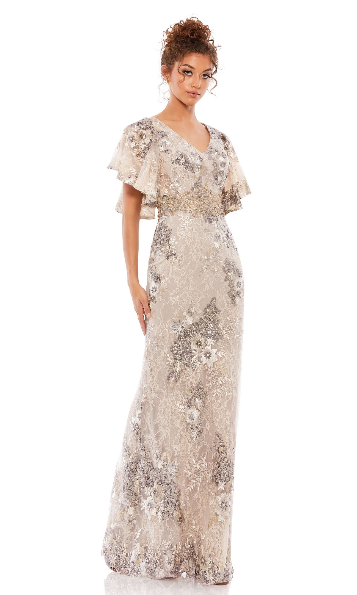 A woman wears the Mac Duggal 67842 Flutter-Sleeve Long Formal Dress in light beige, featuring floral lace patterns and sequin embellishments, standing against a plain white background.